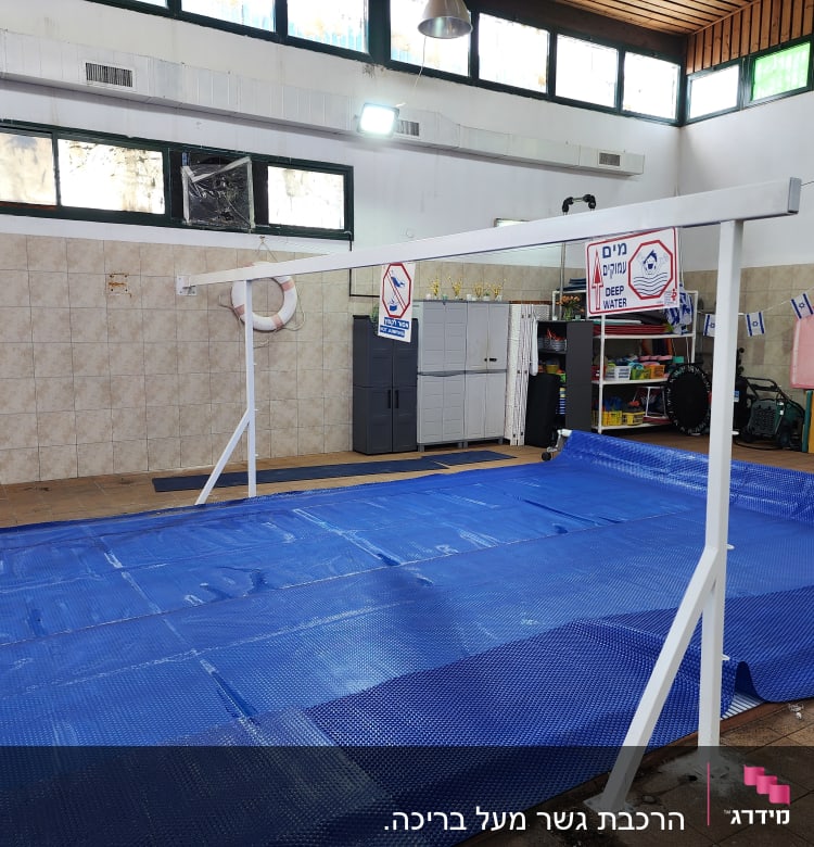 מסגרת מתכת לבנה מעל בריכה מכוסה בכיסוי כחול